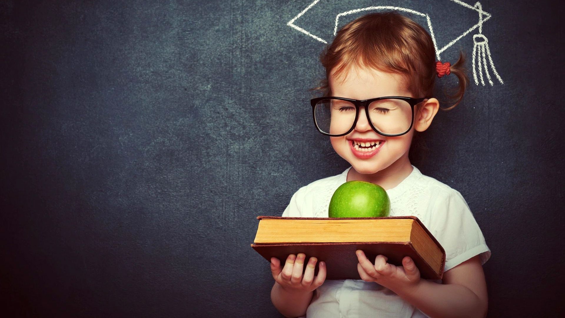 A little girl holding an apple and book