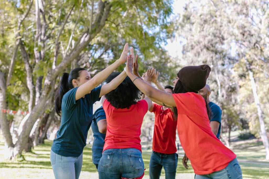 A group of people standing in the grass with their hands up.