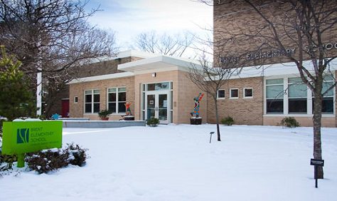 A building with snow on the ground and trees in front of it.