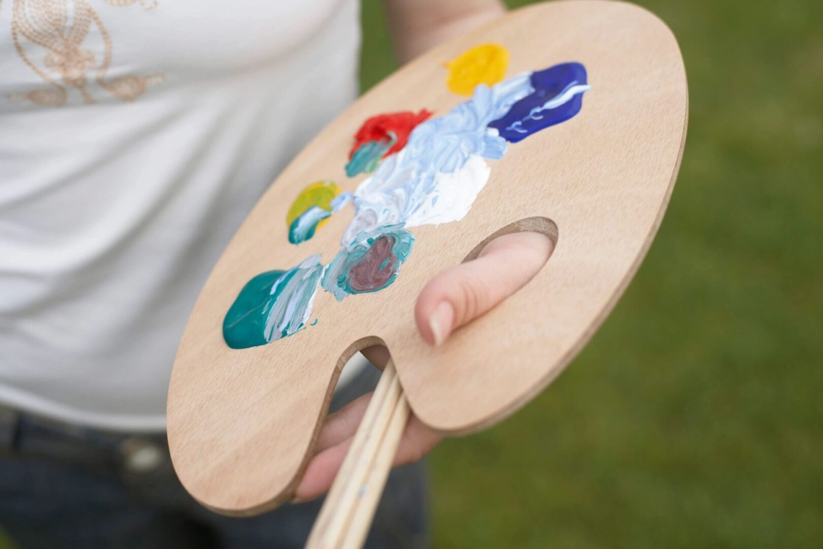 A person holding an art palette with paint on it.